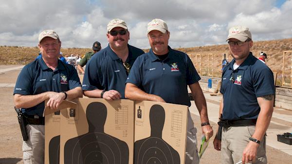 Four Competitors Proudly Standing Behind Their Silhouette Targets After a Match