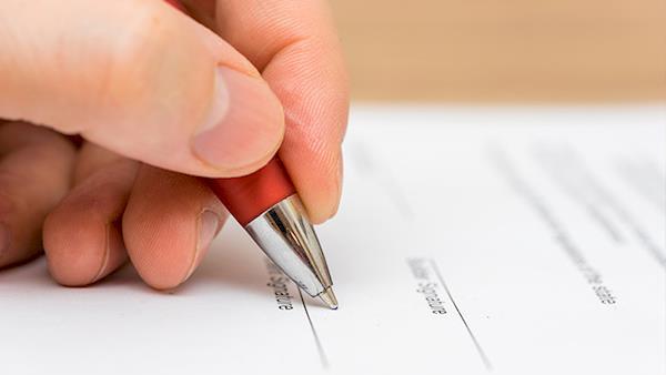 Closeup of a Person with a Pen Filling Out Paper Work